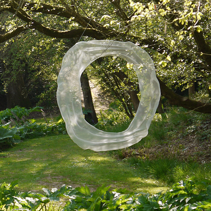 A white abstract and figurative suspended mesh sculpture in a summerly garden