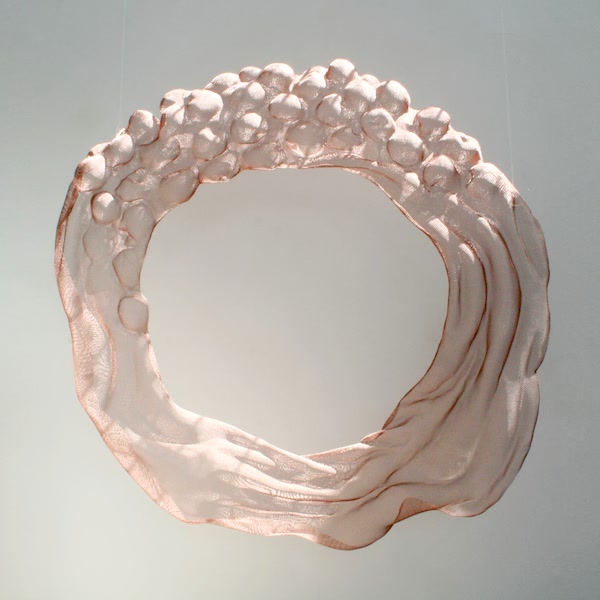 A compsition of drape and fruit as a circular suspended artwork