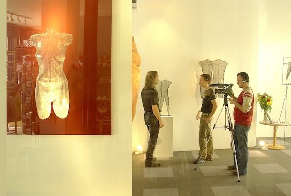 Sculptor in front of his body sculptures with interview team