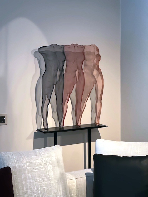 Three figurines are composed to one half-transparent artwork, positioned on a steel podestal