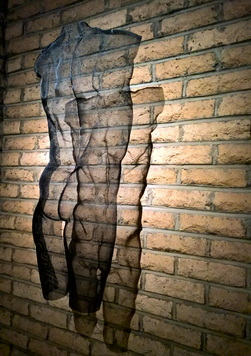 A modern ambiente is decorated with a large mirror reflecting the portrait sculptuer EVE by Daivd Begbie