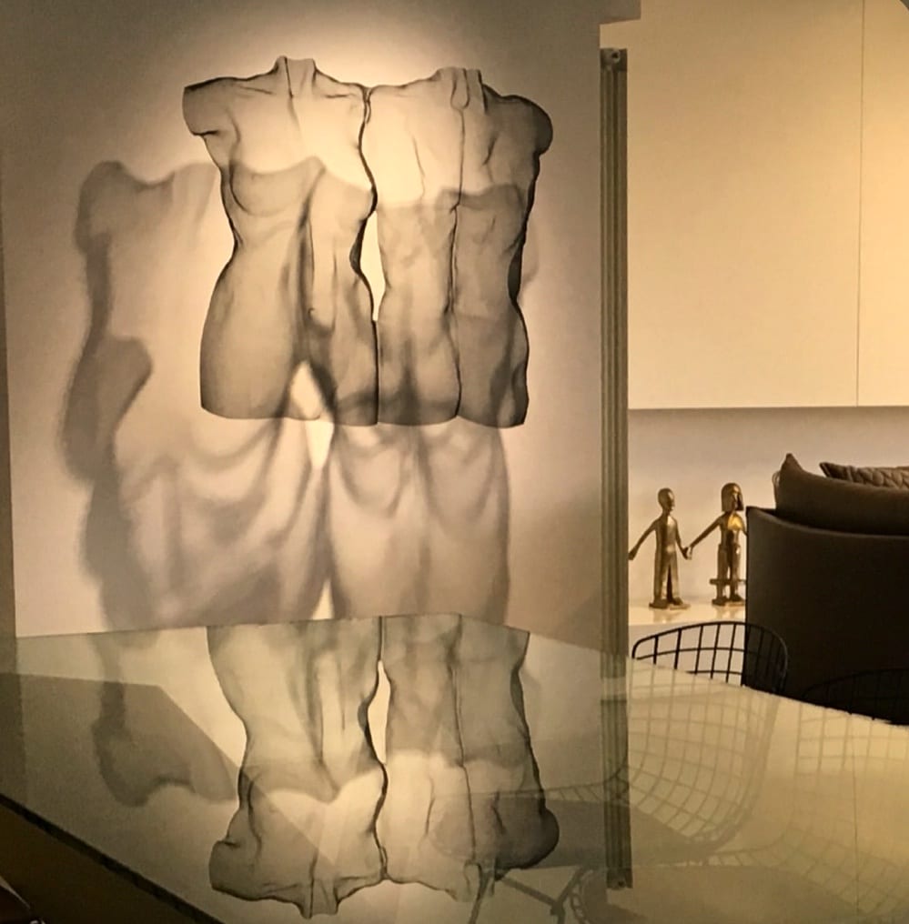 A modern figurative sculpture is suspended as a center piece in a living room.