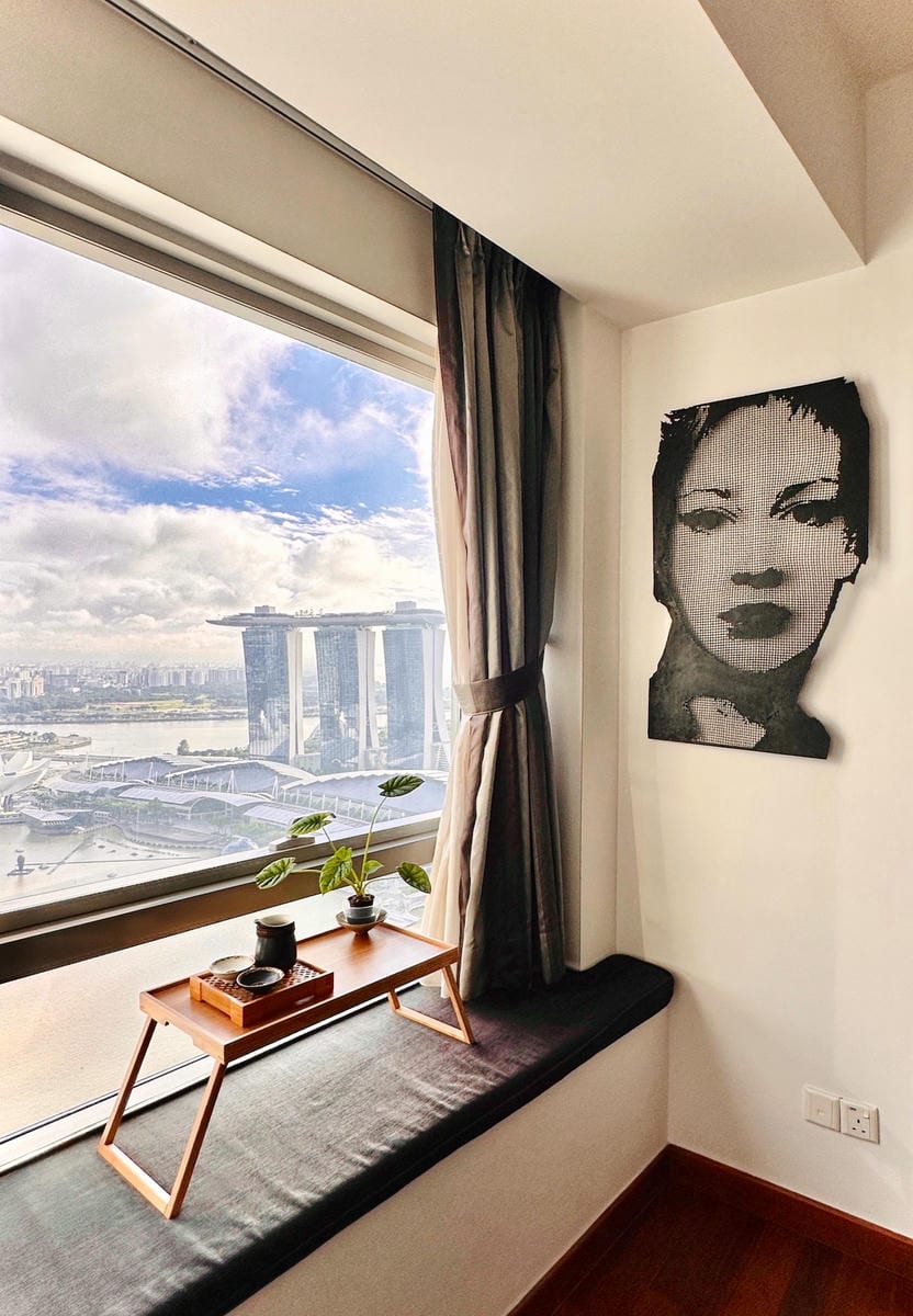 View through a window overlooking the Marina Bay in Singapore - with a female portrait sculpture titled EVE