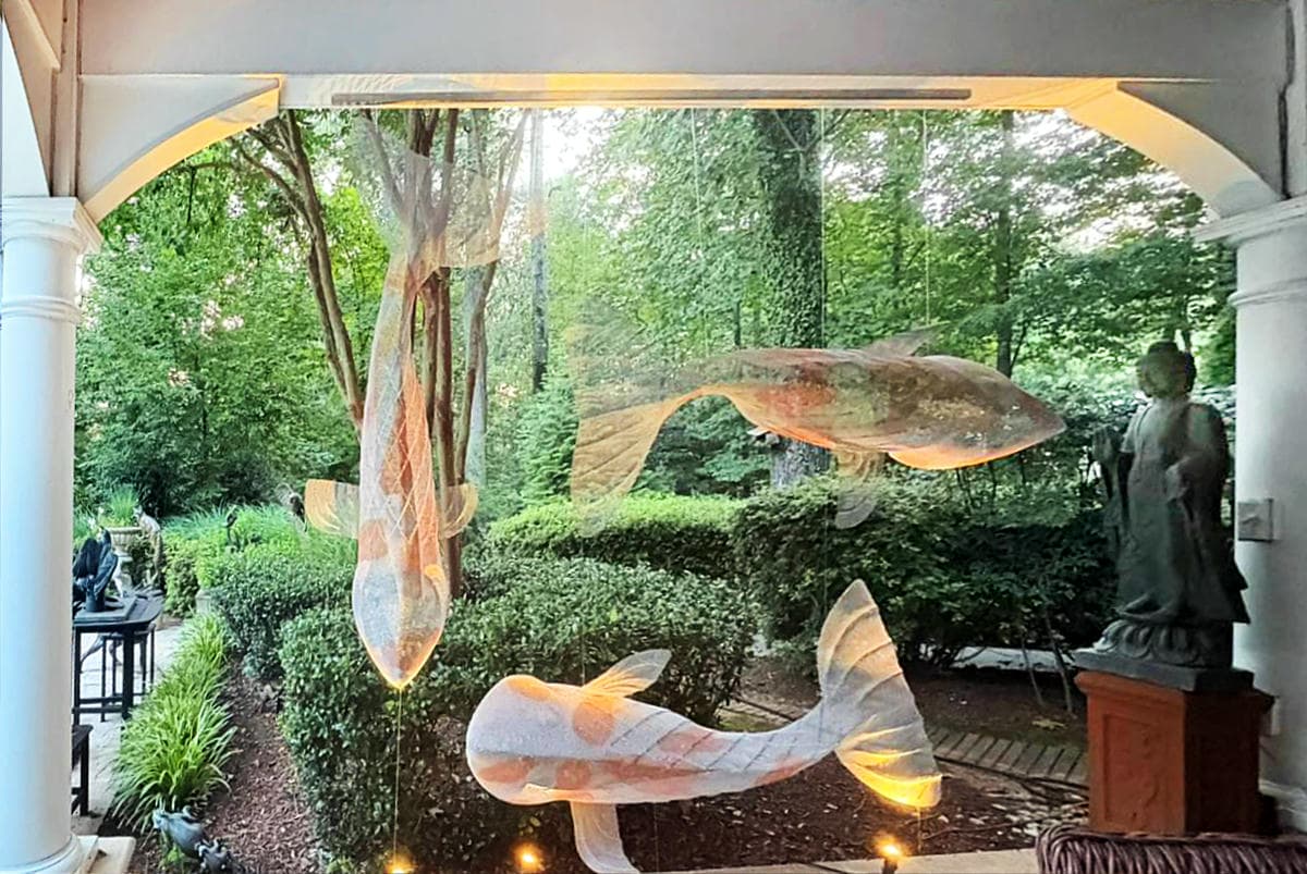 Three koi sculptures are positioned in a garden pavilion