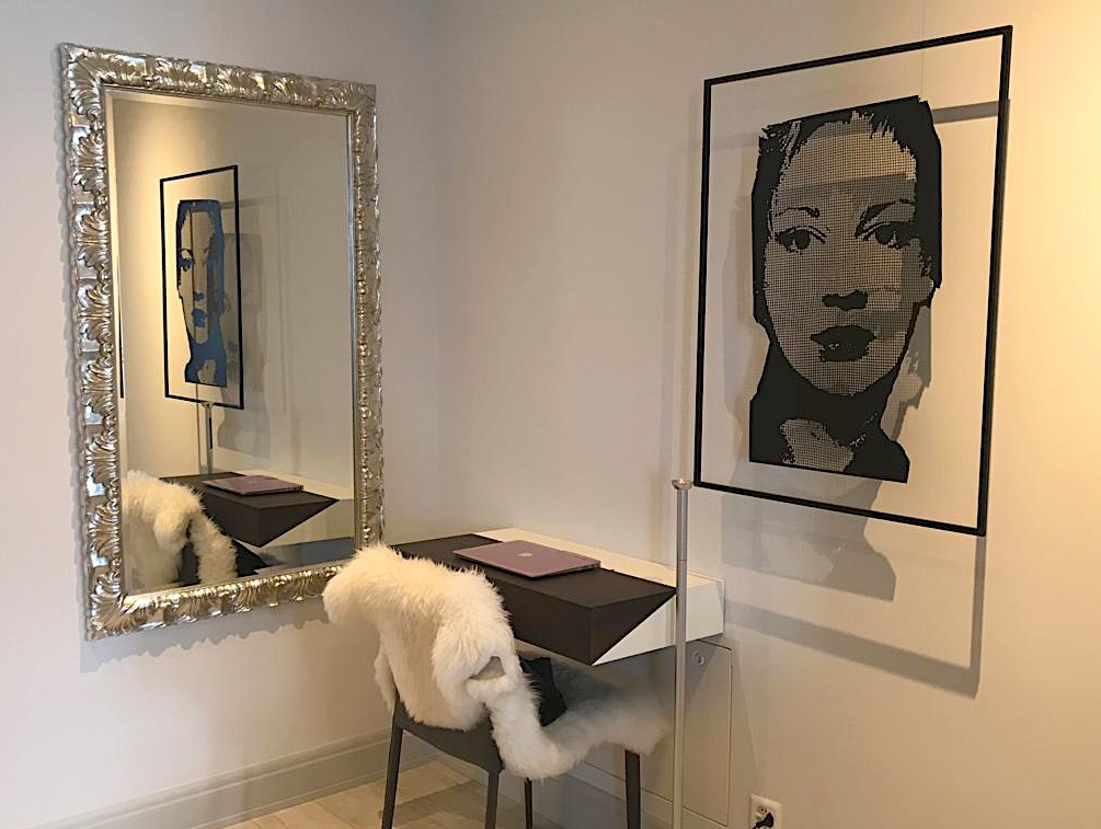 A modern ambiente is decorated with a large mirror reflecting the portrait sculptuer EVE by Daivd Begbie
